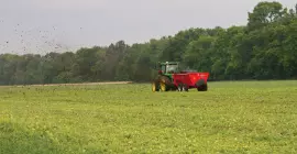 SL 124 au loin distribuant du fumier dans un champ.