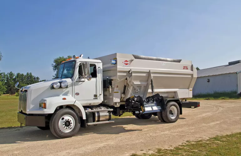 Distributrice BTC 155 portée sur camion stationnée dans une allée de gravier.
