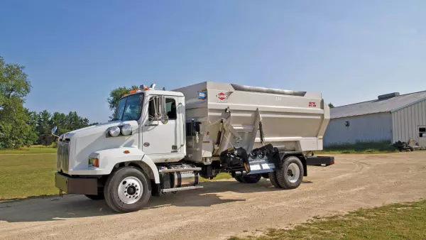 Distributrice BTC 155 portée sur camion stationnée dans une allée de gravier.